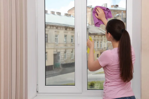 Wanita Muda Membersihkan Kaca Jendela Dengan Kain Dan Deterjen Rumah — Stok Foto