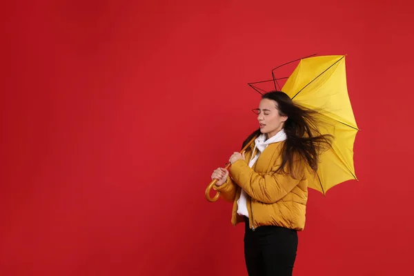 赤い背景に風の突風に巻き込まれた傘を持つ女性 テキストのスペース — ストック写真