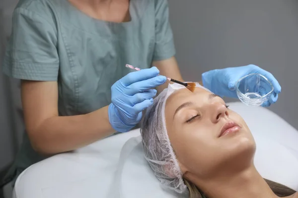 美容师在美容院病人脸上应用化学剥皮产品 — 图库照片