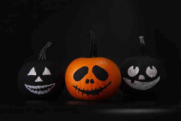 Halloween celebration. Pumpkins with drawn faces on table in darkness