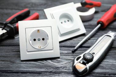Elektrik prizleri ve elektrikli aletler siyah ahşap masada, yakın plan.
