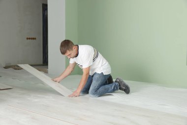 Adam odaya yeni kaplama döşeme kuruyor