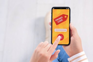Akıllı telefondaki tanıtım kodunu bulanık arka plana karşı etkinleştiren kadın, yakın plan. Metin için boşluk
