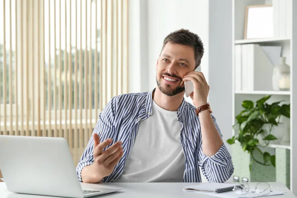 Ofiste Dizüstü Bilgisayarla Çalışırken Akıllı Telefondan Konuşan Mutlu Adam — Stok fotoğraf