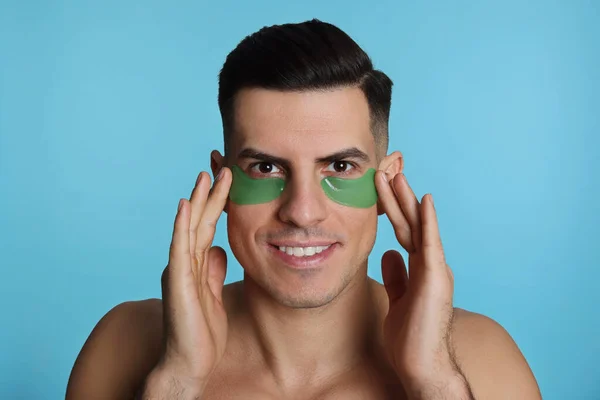 Man Applying Green Eye Patches Light Blue Background — Stock Photo, Image