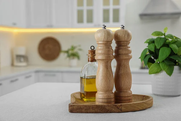 Wooden salt and pepper shakers, bottle of oil on white table indoors, space for text