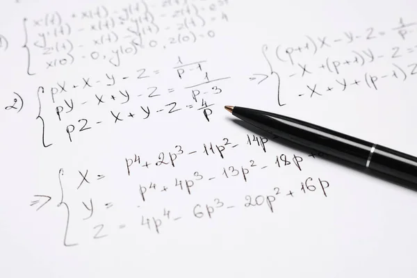 Sheet of paper with mathematical formulas and pen, closeup