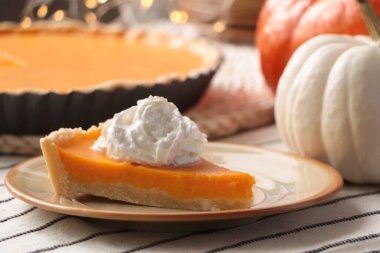 Piece of fresh homemade pumpkin pie with whipped cream on table
