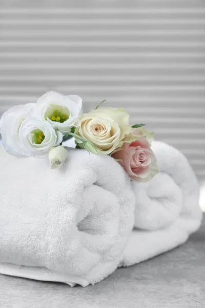 Gerollte Handtücher Und Blumen Auf Grauem Tisch Drinnen — Stockfoto