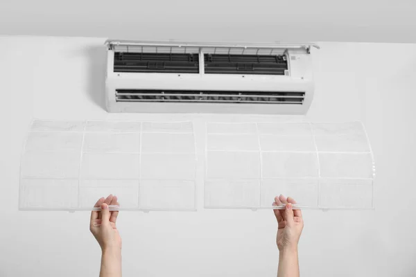Woman holding air conditioner filters indoors, closeup