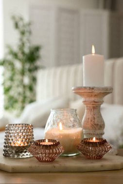 Odanın ahşap masasında kokulu mumlar ve şamdanlar.