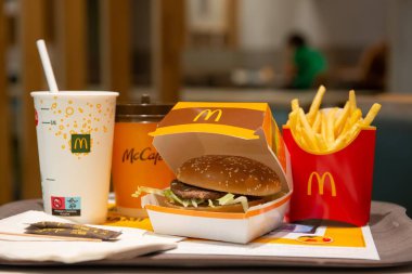 McDonald 's patates kızartması, hamburger ve içecekler masada.