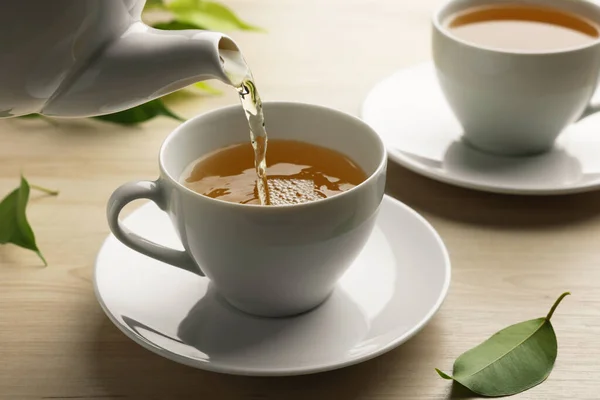 Pouring Green Tea White Cup Saucer Leaves Wooden Table Closeup — Stock Photo, Image