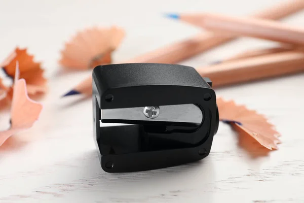 Black pencil sharpener on white wooden table, closeup