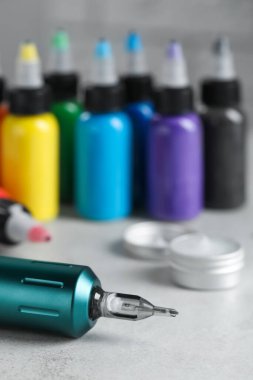 Modern profesyonel dövme makinesi ve beyaz masa üzerindeki renkli mürekkepler, metin için boşluk
