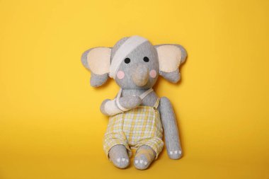 Sarı arka planda bandajlı oyuncak fil