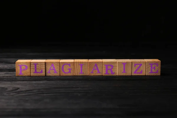 木製のキューブと単語黒のテーブルの上にPlagiarize — ストック写真
