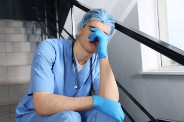 Hastanede merdivenlerde oturan bitkin doktor.