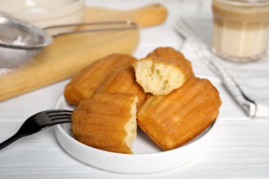 Delicious madeleine cakes on white wooden table, closeup