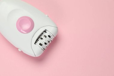 Pembe arka planda modern epilatör, üst manzara. Metin için boşluk