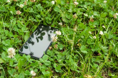 Açık havada yeşil çimlerde akıllı telefon, mesaj için yer. Kayıp eşya bürosu