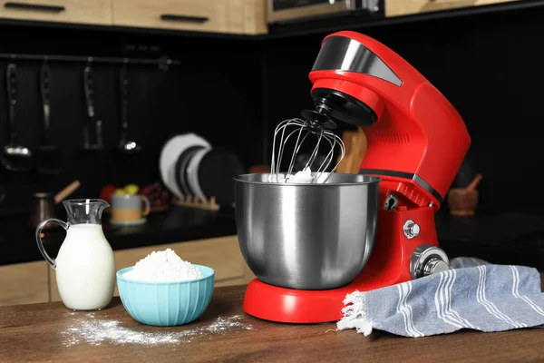 Modern red stand mixer and ingredients on wooden table in kitchen