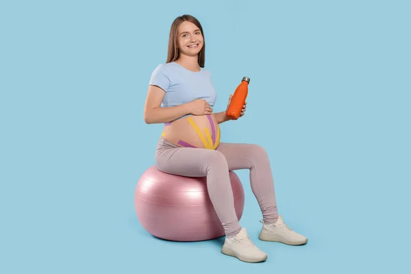 Gravid Kvinna Med Kinesio Tejp Hålla Vattenflaska Fitball Mot Ljusblå — Stockfoto