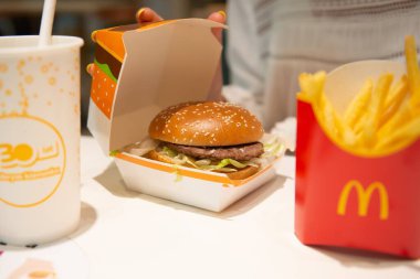 SAVAŞ, POLAND - SEPTEMBER 04, 2022: McDonald 's burgerli kadın, kafedeki masada patates kızartması ve içecek, yakın plan