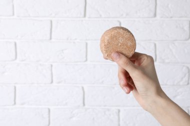 Tuğla beyaz duvara karşı sağlam şampuan tutan kadın, yakın plan. Metin için boşluk