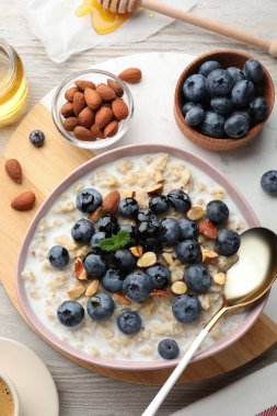 Flat lay composition with tasty oatmeal porridge and ingredients served on wooden table. Healthy meal