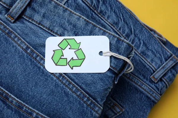 Stack of jeans with recycling label, closeup