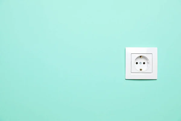 Power socket on turquoise wall, space for text. Electrical supply