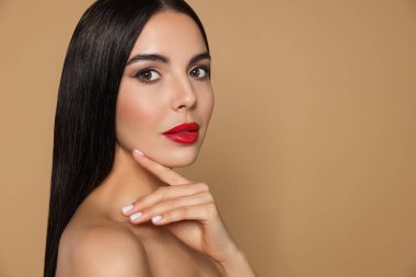Bej arka planda güzel kırmızı ruj süren genç bir kadının portresi.
