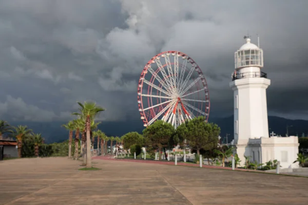 雨云下的大型摩天轮和灯塔的朦胧景象 — 图库照片