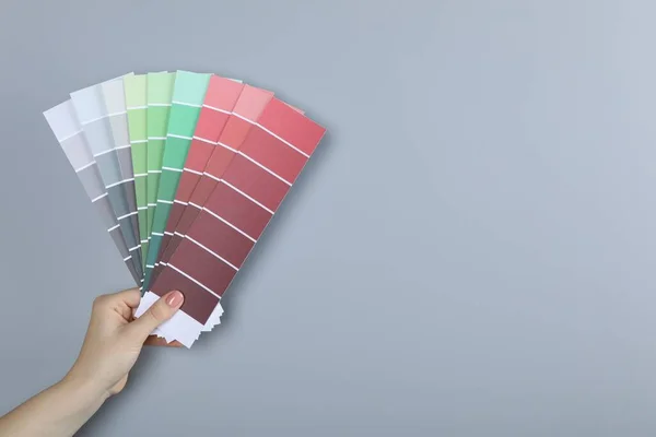 Kobieta Odłamkami Farby Wybierając Kolor Pobliżu Szarej Ściany Zbliżenie Projekt — Zdjęcie stockowe