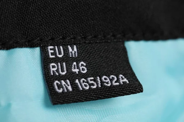 Clothing label on turquoise garment, closeup view