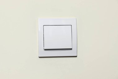 Modern plastic light switch on white wall, closeup