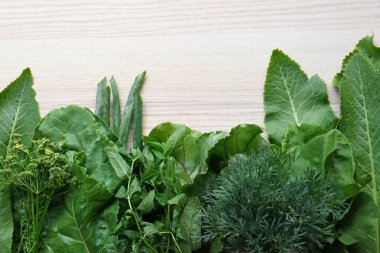 Beyaz ahşap masada farklı otlar, düz uzanmış.