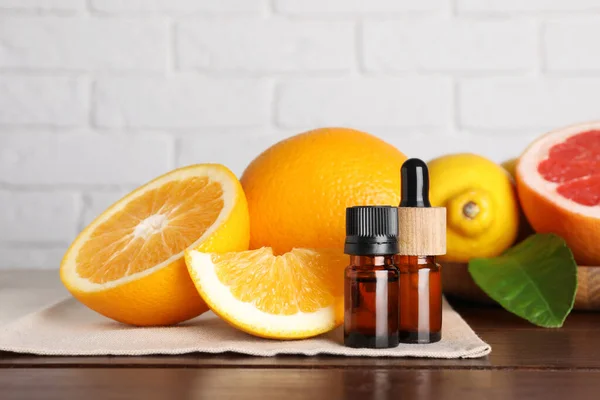 木桌上白色砖墙上装有不同柑橘类水果和叶子的香精油盒 — 图库照片