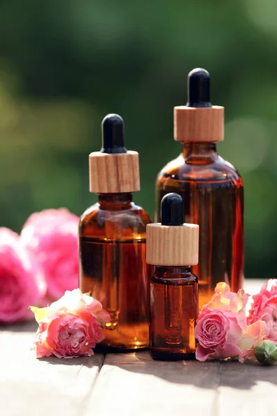 Bottles Rose Essential Oil Flowers Wooden Table Outdoors — Stockfoto