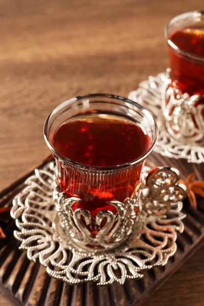 Glasses of traditional Turkish tea in vintage holders on wooden table, closeup