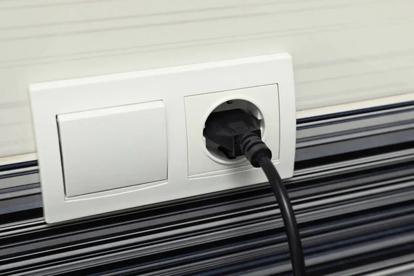 Power socket and plug on color wall, closeup