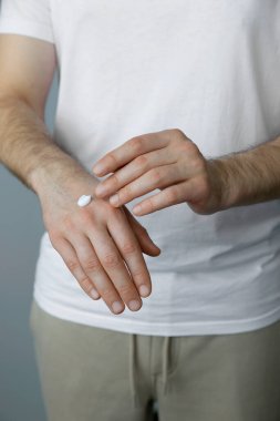 Gri arka plana krem süren adam, yakın plan.