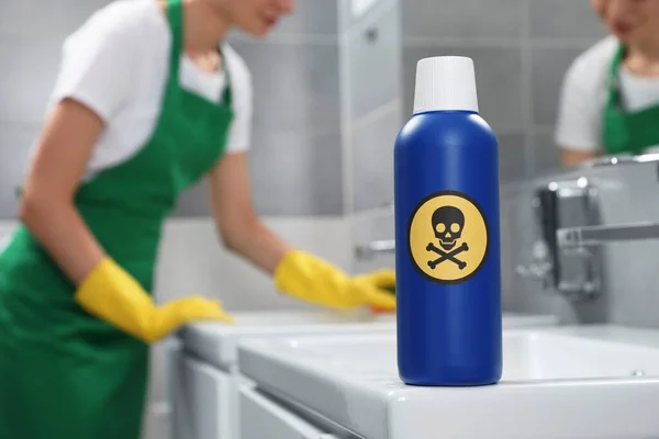 Bottle of toxic household chemical with warning sign in bathroom