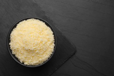 Siyah masanın üstünde rendelenmiş parmesan peyniri olan bir kase. Metin için boşluk