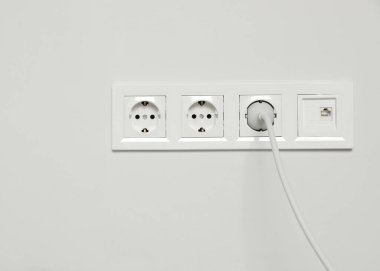 İçerideki beyaz duvarda prize takılmış güç prizleri. Elektrik arzı