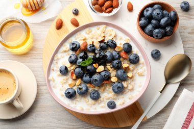Flat lay composition with tasty oatmeal porridge and ingredients served on wooden table. Healthy meal