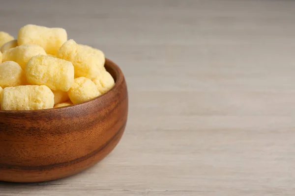 Bowl of corn sticks on wooden table, closeup. Space for text