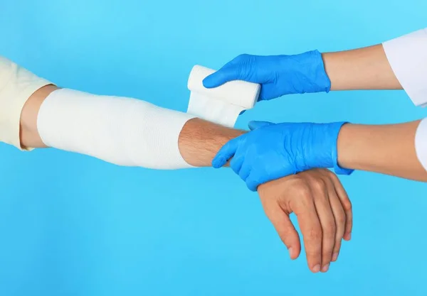 Läkare Applicera Medicinsk Bandage Patientens Arm Ljusblå Bakgrund Närbild — Stockfoto