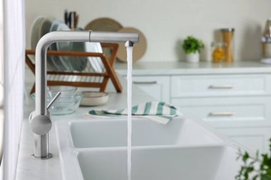 Stream of water flowing from tap in kitchen, space for text